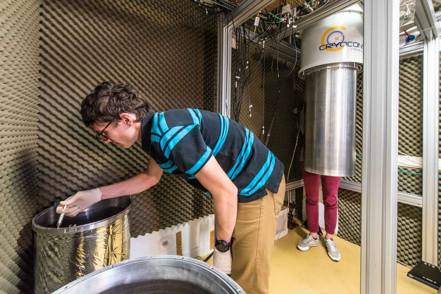 LPA. Laboratoire Pierre Aigrin . Equipe de Takis Kontos. Recherche sur les circuits quantiques hybrides. Lauriane Contamin, doctorante et Mathieu Delbecq , chercheur referment le cryostat afin de mettre en route une nouvelle expérience. Ils remontent, comme des poupées russes, les protections cylyndriques du cryostat, afin d'isoler thermiquement et électro-magnétiquement le crysostat et l'échantillon qu'il contient. Cet appareil est conçu pour atteindre une température proche du zéro absolu, à laquelle il est possible de piéger et "d'immobiliser" des particules telles que les électrons ou les photons.